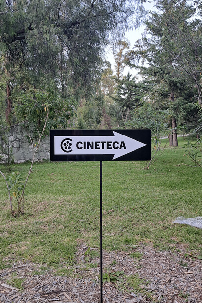 The sign pointing toward Cineteca Nacional Chapultepec, Mexico City, Mexico surrounded by greenery, symbolizing the venue's close connection with its natural surroundings