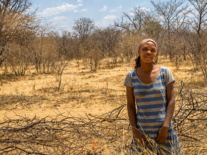 A family poses in a dry, drought-affected field, highlighting the human impact of poverty and environmental stress