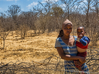 An African family with their child stands in a parched landscape shaped by drought and economic vulnerability