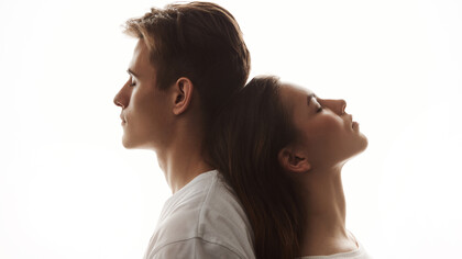 A man and woman share a tender moment of love as she rests her head on his back, her eyes peacefully closed