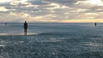 Antony Gormley Another Place, 1997, Antony Gormley’s Another Place features 100 cast-iron figures facing the sea along Crosby Beach, exploring humanity’s relationship with nature, time, solitude, and existence. Each life-sized figure, modelled on Gormley’s own body, stands motionless against shifting tides and weather, symbolizing reflection, resilience, and the universal human search for meaning and connection