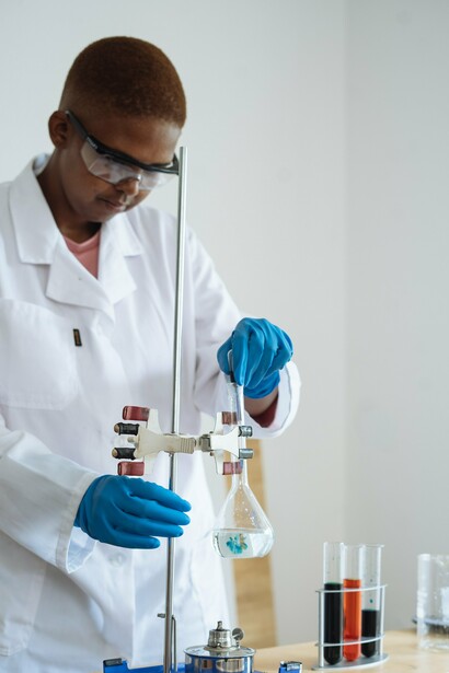 A person in a lab coat and gloves researching how synthetic biology can be used to reduce plastic waste