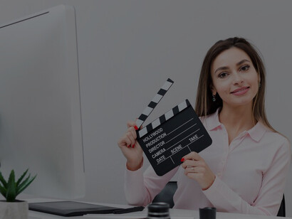 A female screenwriter poses confidently at her desk with a clapperboard in hand