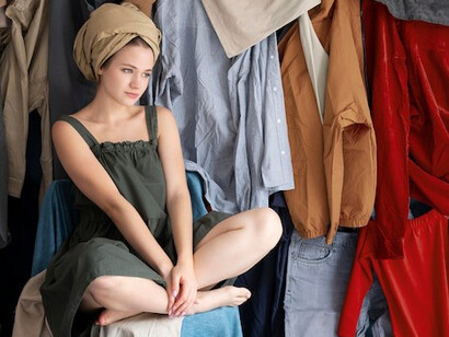 A woman overwhelmed by piles of fast fashion clothing