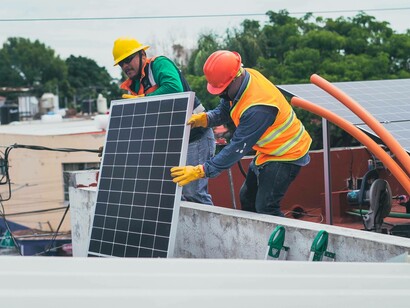 Construction workers lifting an energy-efficient solar panel to a building