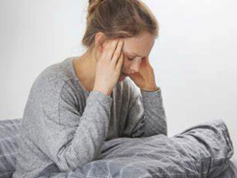 A woman with food intolerances in bed, holding her stomach in discomfort, battling the pain caused by her food allergies
