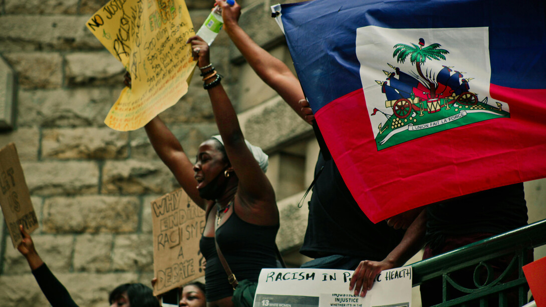 People at a demonstration carrying a Haitian flag