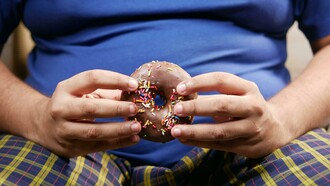 A person holding a doughnut, symbolizing the irresistible appeal of sugary, ultra-processed foods