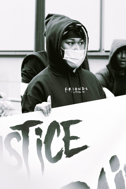 In a grayscale image, a woman holds a "Black Lives Matter" sign in Brest, France