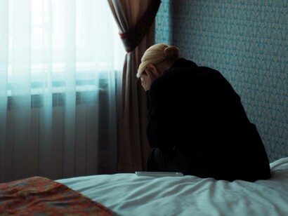A woman depressed is crying on the edge of her bed