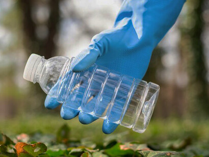 A man collects plastic waste in a polluted park, highlighting the urgent need for bioplastics, eco-friendly products, and effective recycling solutions