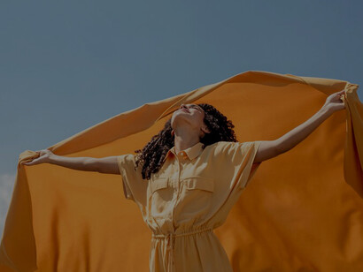 The spirit of liberation and authenticity as a woman gracefully holds a yellow cloth in nature, symbolizing freedom in this captivating image