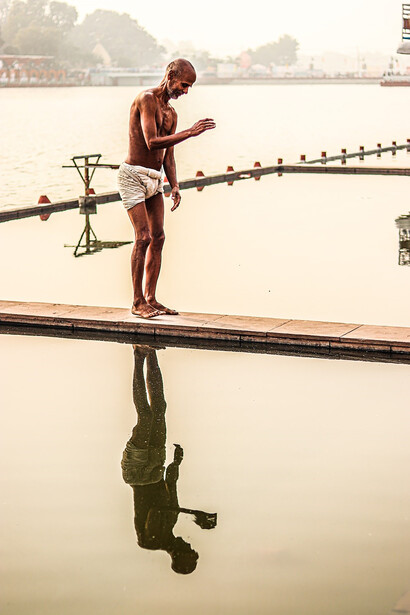 Basking beside a calm body of water, a man finds repose on a wooden dock, engaging in yoga asanas and partaking in exercises that infuse his body with invigorating energy
