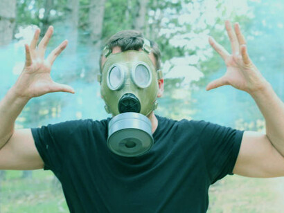 A man wearing a rubber mask in a toxic environment, symbolizing the nuclear threat and the impact of climate change