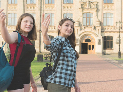 Two high school girls smiling and looking at the camera, capturing a moment of camaraderie and youthful energy