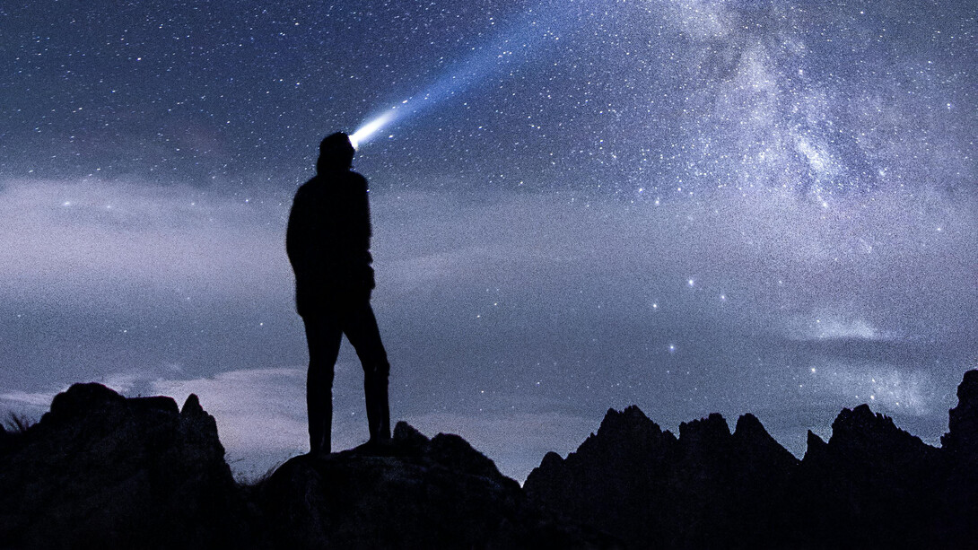 A human figure contemplates a falling star and the night sky