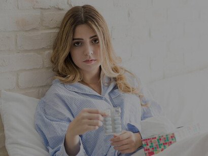 Woman in cozy pajamas experiencing menstrual cramps while resting in bed, highlighting the discomfort and challenges of menstruation