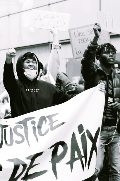 A black-and-white photo of a woman holding a "Black Lives Matter" sign in Brest, France