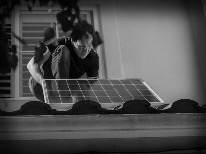 A man installs solar panels on the roof of a residential house