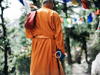 Against the backdrop of towering peaks, a monk moves with purpose along the rugged paths of Khumbu, a testament to spiritual devotion amidst the trials of high-altitude trekking