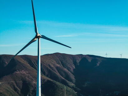 A wind turbine, source of renewable energy, against a mountain backdrop