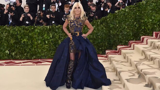 Donatella Versace in an intricately embellished ensemble, symbolizing the luxury and theatrical elegance of the Versace house