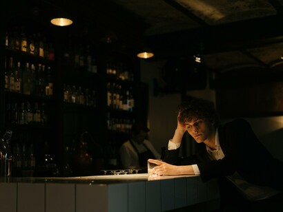 A man sat alone at a bar with a drink