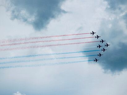 Aircrafts in flight above Circuit Le Mans in Le Mans, France, trailing striking contrails of blue, red, and white
