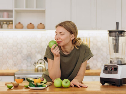 In her kitchen sanctuary, a woman prepares a colorful smoothie bowl brimming with chia seeds, showcasing their ability to enhance heart health and aid digestion effortlessly