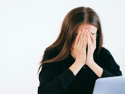 A woman covering her face with her hands as her way to cope with the stress she's experiencing