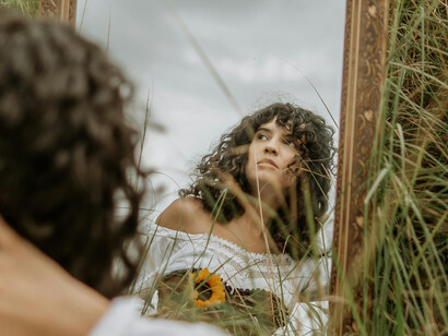 A mirror reflect the image of a young woman on a field