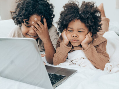 Young boys stare blankly at the screen of a laptop, addicted to the feeling of escapism that comes with the distraction of technology