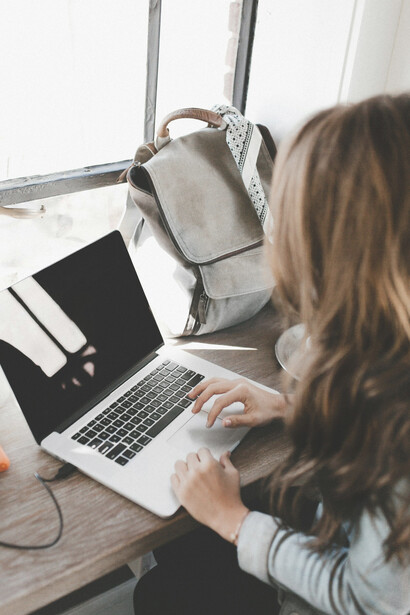 A woman sitting at a black table, writing in a white book near a window, explores themes of literary authenticity, cultural appropriation, book criticism, author identity, and creative freedom