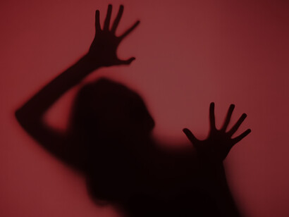 In a chilling red shadow, the silhouettes of a woman's hands evoke an eerie presence