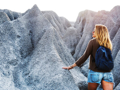 A woman ascends the mountain trail, embracing the serene beauty of nature as she journeys toward the peak