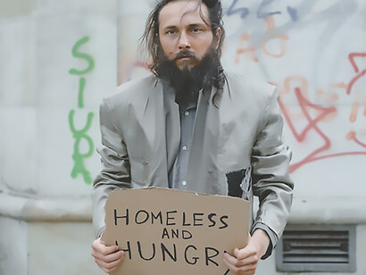 Amidst adversity, a man holds a poignant cardboard sign proclaiming his hunger and desperate need for food, shedding light on the unmet challenges faced by those in need