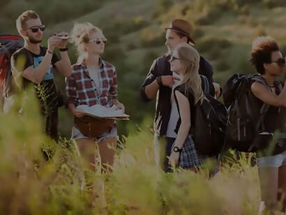 In a picturesque canyon, a group of young friends with backpacks revels in the breathtaking view, epitomizing the joy of shared exploration and travel