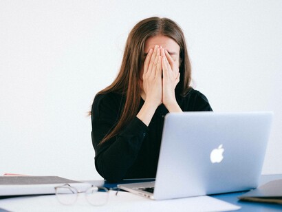 A woman shielding her face with her hands as she deals with her stress
