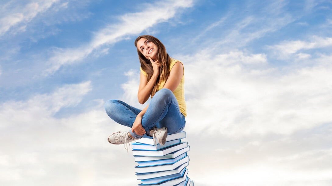 A girl sitting on books, surrounded by a focused study environment, applying study techniques and following a study plan