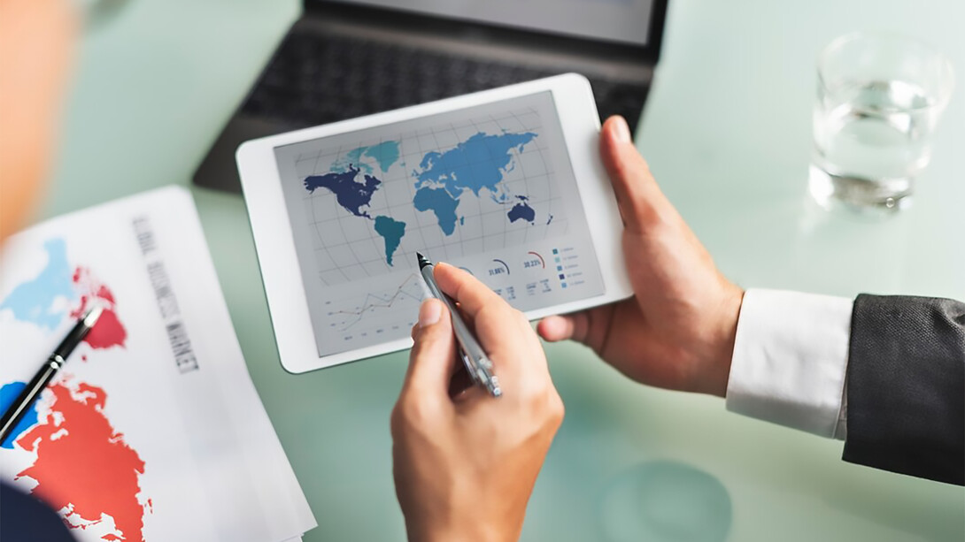Economists analyzing data on a screen filled with global charts