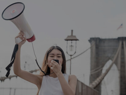 A woman using a megaphone at the Brooklyn Bridge, advocating during a protest