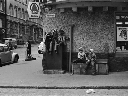 Eeva Rista, Three girls reading on top of a distribution cabinet at the corner of Meritullinkatu and Liisankatu. Two children sit next to them on a wooden crate. Grocery shop Spar Salonen on the corner, with Lenina nappies advertised in the window, 1970. Courtesy of Helsinki City Museum