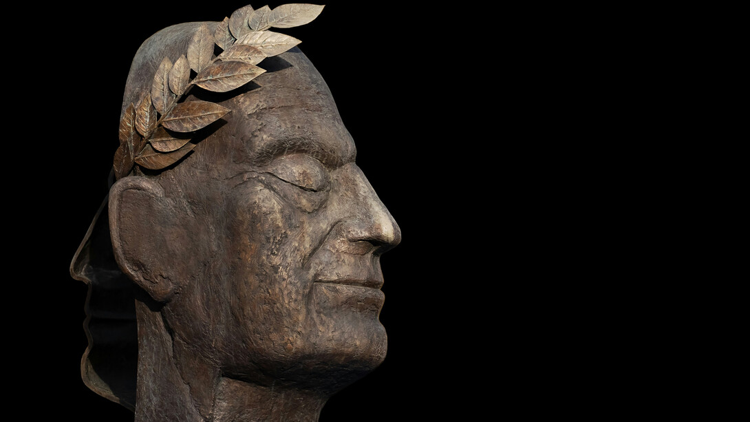A bronze bust of Julius Caesar facing the dark
