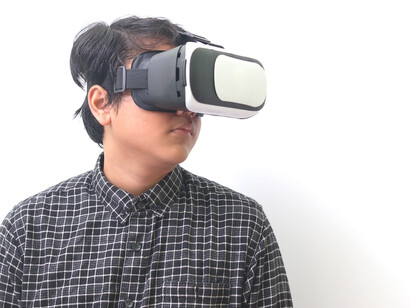 Immersed in the world of virtual reality, an Asian man dons VR glasses and indulges in thrilling gaming experiences