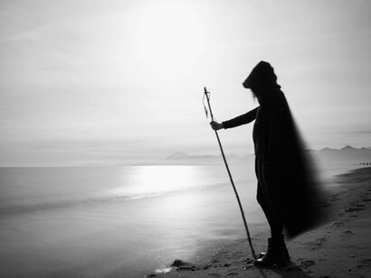 A lonely silhouette of a person, standing near a calm sea