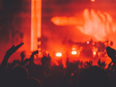 In the dimly lit ambiance of the venue, a striking silhouette photo captures the essence of a captivated crowd, their silhouettes etched against the glowing stage, eagerly watching the DJ's performance, united by the pulsating beats that resonate through the night