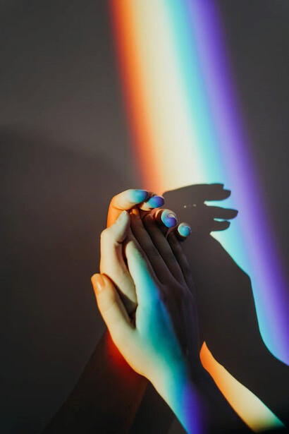 People's hands painted in a vibrant rainbow of colors