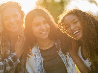 A group of teenagers joyfully gathers outdoors, relishing each other's company and embracing the simple pleasures of togetherness