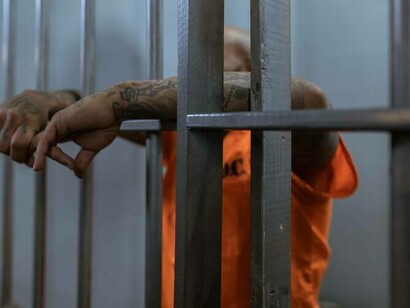 A prisoner with hands extending from the prison cell praying for a way out