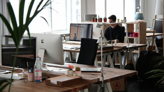 A man sits in front of a computer, surrounded by the clean lines and simplicity of a minimalist office space in Berlin, Germany